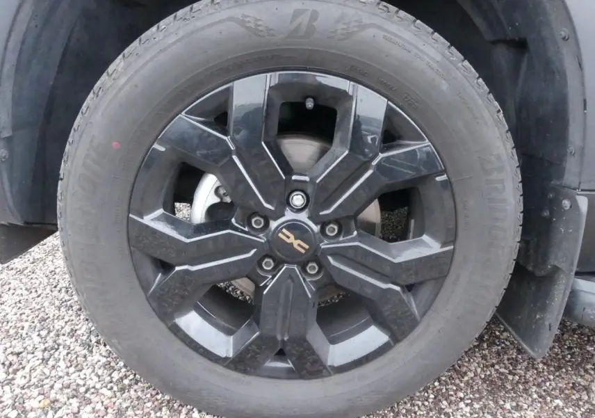 Gros plan sur la jante alliage noire 17 pouces du côté avant droit du Dacia Duster noir 2023.