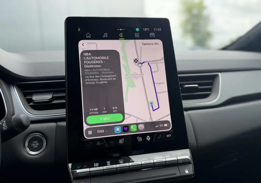 Vue intérieure centrée sur l'écran tactile vertical du tableau de bord du Renault Captur gris Rafale, avec navigation affichée.