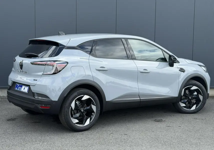 Vue 3/4 arrière droite du Renault Captur gris Rafale avec jantes noires et blanches, vitres teintées et antenne requin.