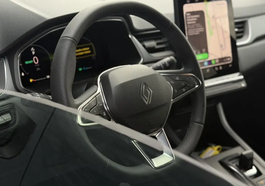 Vue rapprochée du volant en textile noir et du tableau de bord numérique du Renault Captur 2026.