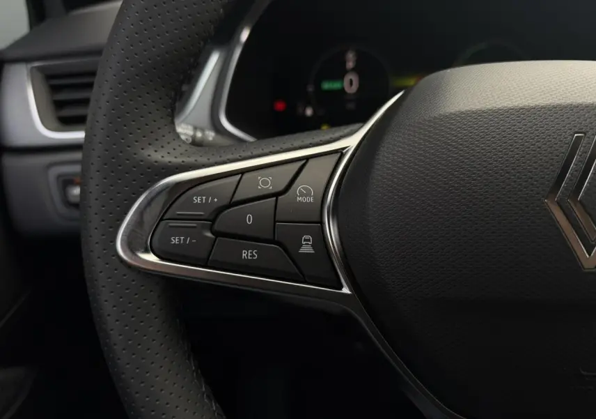 Gros plan sur le volant noir perforé du Renault Captur gris Rafale, avec commandes multifonctions à gauche visibles.