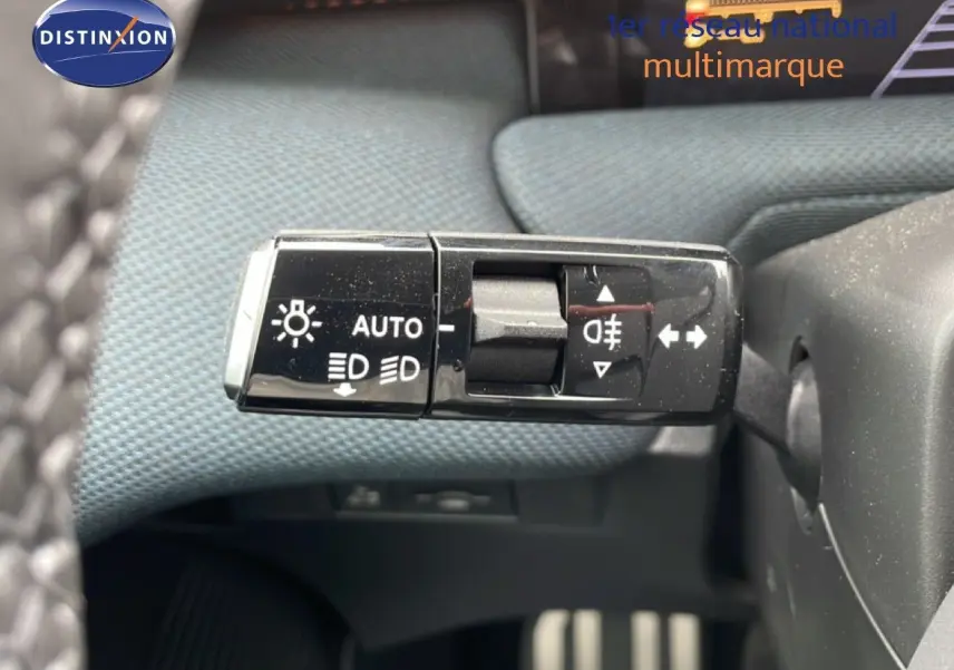 Gros plan sur la commande des feux du Citroën C5 Aircross 2026, avec tissu bleu et plastique noir en arrière-plan.