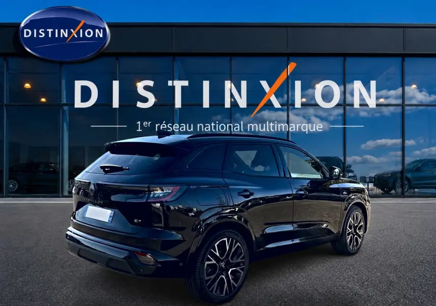 Renault Austral noir en 3/4 arrière droit, avec jantes alu et becquet arrière, devant un bâtiment Distinxion.