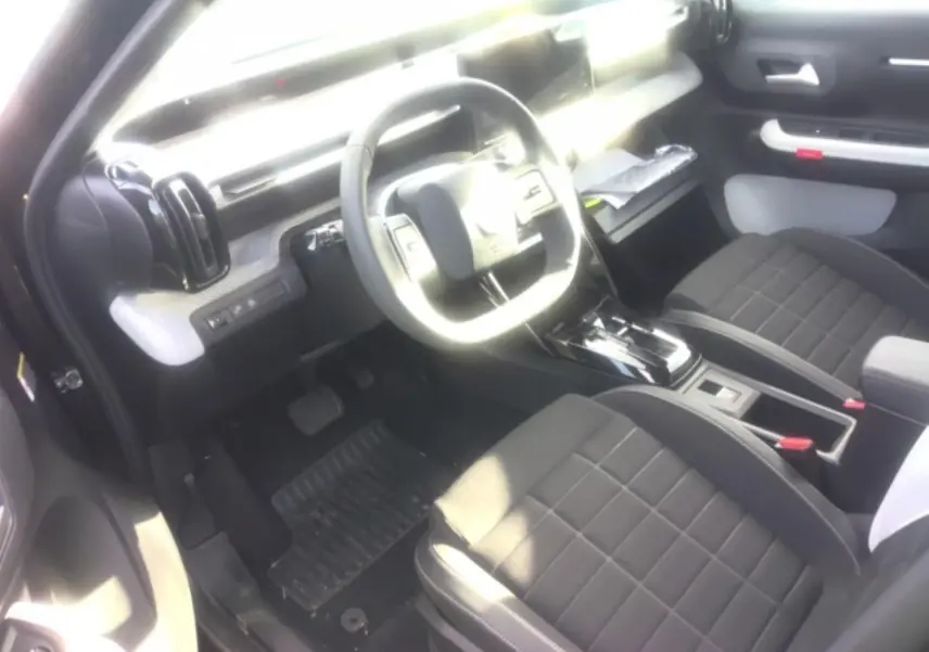 Vue intérieure côté conducteur de la Citroën C3 ë-113 BERLINE Max 2025 avec sièges noirs et tableau de bord moderne.