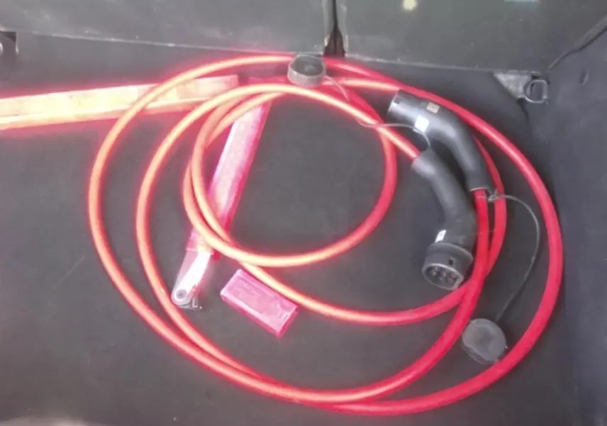 Câble de recharge électrique rouge dans le coffre noir d'une Citroën C3 ë-113 BERLINE Max 2025.