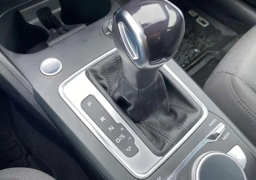 Gros plan sur le levier de vitesses automatique noir et argenté de l’Audi Q2 2023, avec commandes MMI autour.