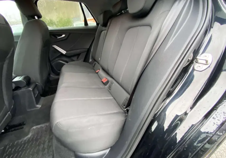 Vue intérieure côté droit sur la banquette arrière grise d’un Audi Q2 noir 2023 avec porte ouverte.