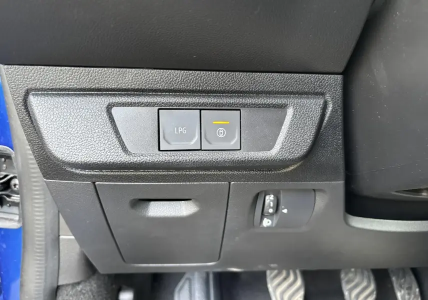 Détail intérieur côté gauche avec boutons LPG et verrouillage, plancher et pédales visibles, portière bleu Iron ouverte.