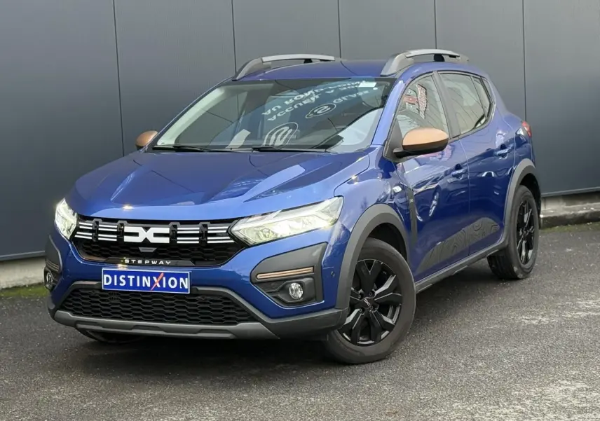 Dacia Sandero Stepway Bleu Iron en 3/4 avant droit avec jantes noires et coques de rétroviseurs cuivrées.