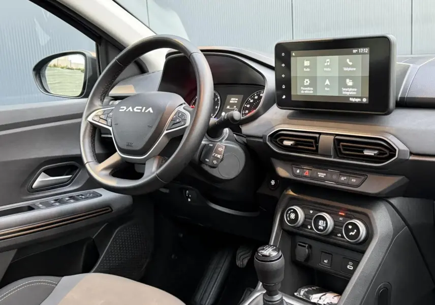 Vue intérieure côté conducteur du tableau de bord et volant Dacia avec écran tactile 8 pouces et commandes au volant.