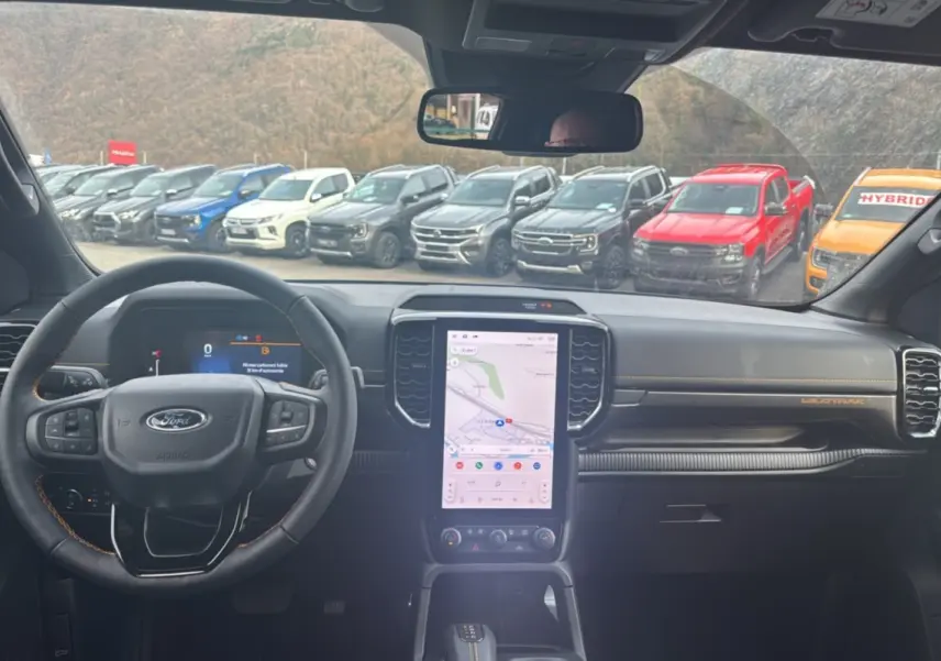 Vue intérieure du Ford Ranger Wildtrak 2025, montrant le tableau de bord noir avec écran tactile vertical et volant multifonctions.