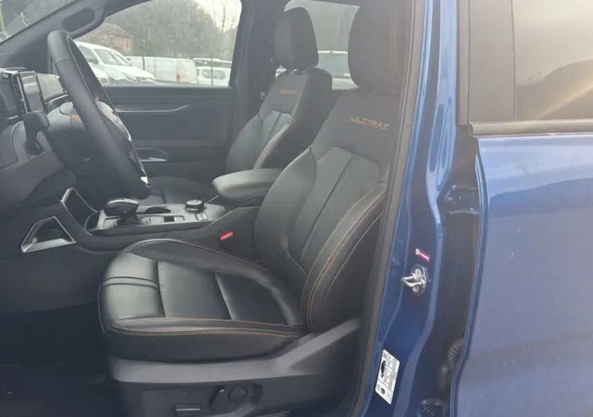Vue intérieure côté conducteur du Ford Ranger Wildtrak 2025 bleu lightning, sièges cuir noirs avec surpiqûres orange.