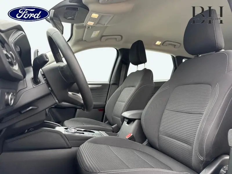 Vue intérieure côté conducteur du Ford Kuga 2023, sièges sport noirs avec coutures blanches et accoudoir central.