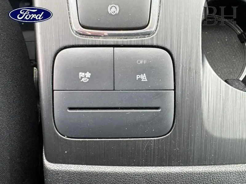 Détail des boutons de commande du système d'aide au stationnement sur console centrale d'une Ford Kuga 2023 gris Solar métallisé.