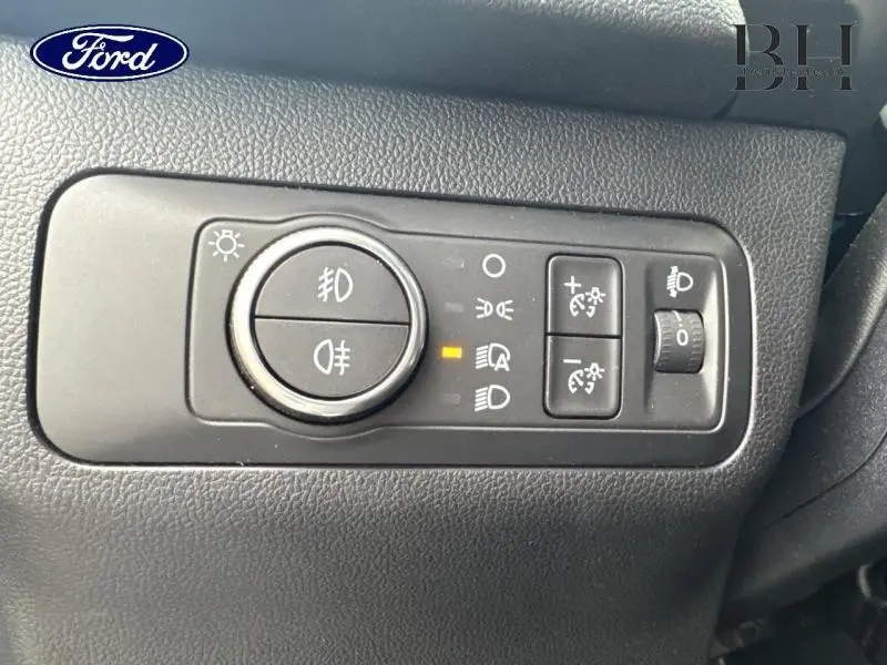 Gros plan sur les commandes d’éclairage intérieures du Ford Kuga 2023, tableau de bord noir texturé.