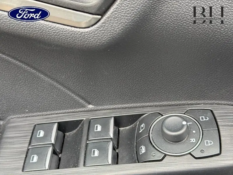 Gros plan sur les commandes de lève-vitres et rétroviseurs côté conducteur du Ford Kuga gris Solar Métallisée 2023.