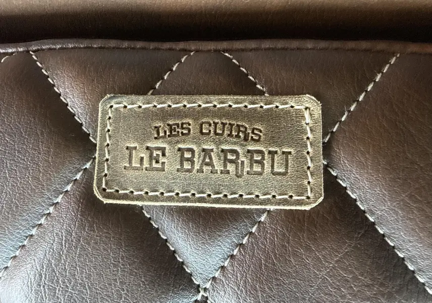 Gros plan sur une étiquette en cuir marron matelassé avec l'inscription "LES CUIRS LE BARBU".
