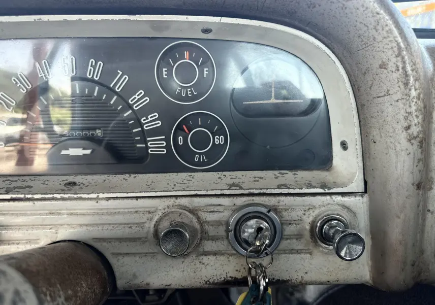 Tableau de bord ancien de Chevrolet C10 Apache 1963, vue frontale sur compteurs et clé de contact insérée.