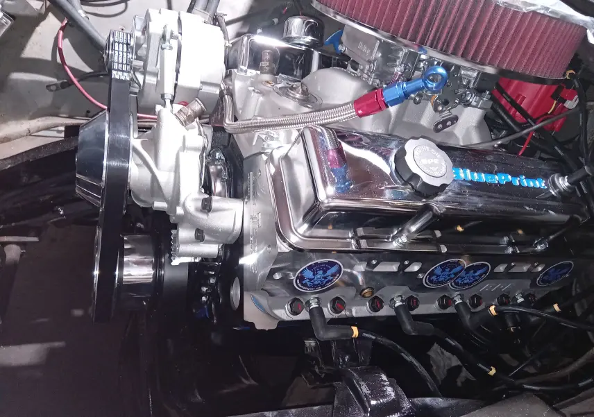 Gros plan sur le moteur V8 chromé avec filtre à air rouge du Chevrolet C10 Apache 1963 bleu, vue latérale droite.