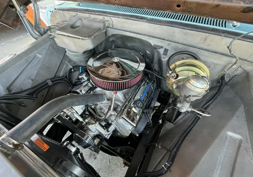Vue rapprochée du moteur V8 chromé dans le compartiment moteur d'une Chevrolet C10 Apache 1963 bleu.