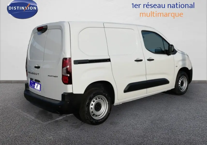 Vue 3/4 arrière droite d’un Peugeot Partner blanc Kaolin, fourgon utilitaire avec protections noires sur les portières.