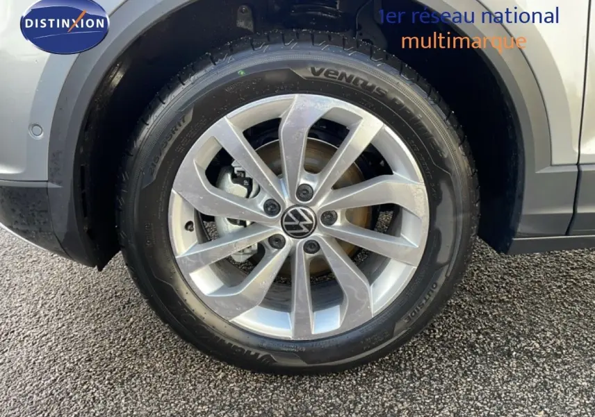 Gros plan sur la roue avant gauche du Volkswagen T-Roc gris pyrite métal, mettant en valeur la jante alliage et le pneu.