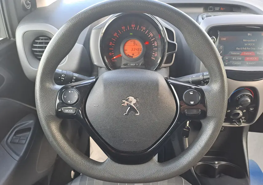 Vue rapprochée du volant noir de la Peugeot 108 2020 avec tableau de bord et écran multimédia visibles.