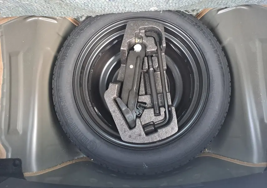 Vue plongeante sur la roue de secours noire d'une Peugeot 108 2020 avec kit de démontage intégré.