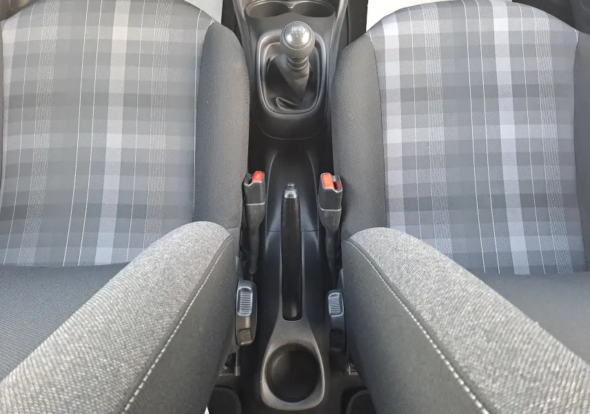 Vue plongeante sur la console centrale et les sièges avant en tissu gris à motifs de la Peugeot 108 noire de 2020.