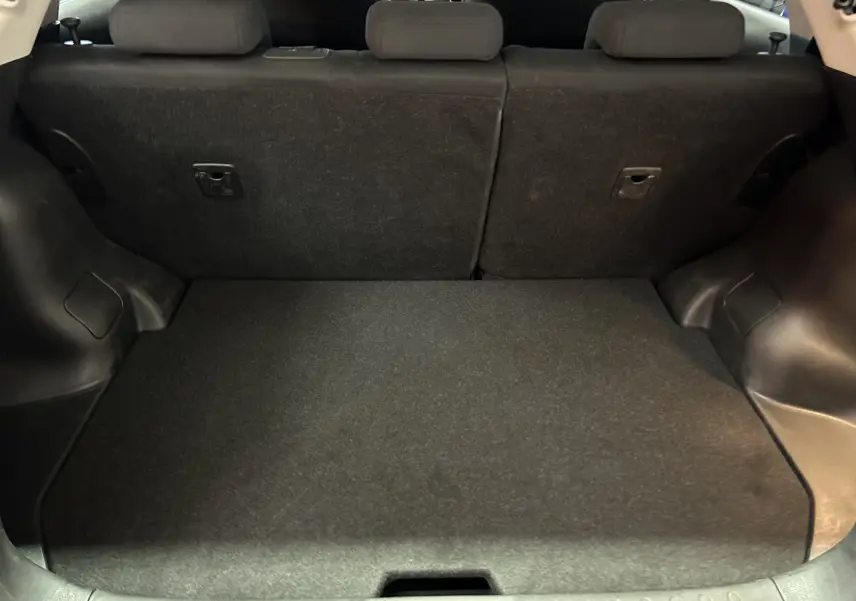 Coffre spacieux du Nissan Juke noir métal vu de l'arrière avec banquette arrière en tissu et plancher plat.