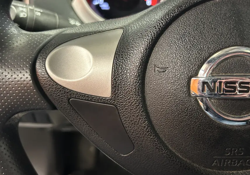 Gros plan sur le volant noir du Nissan Juke 2012, mettant en valeur le logo Nissan chromé au centre.