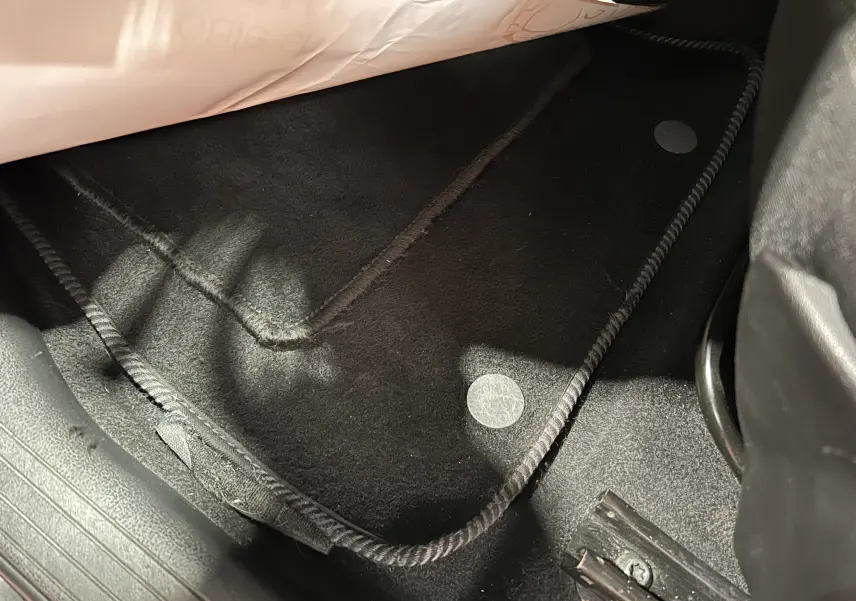 Détail intérieur montrant le tapis de sol noir côté conducteur du Nissan Juke dci 110 Acenta avec attelage, année 2012.