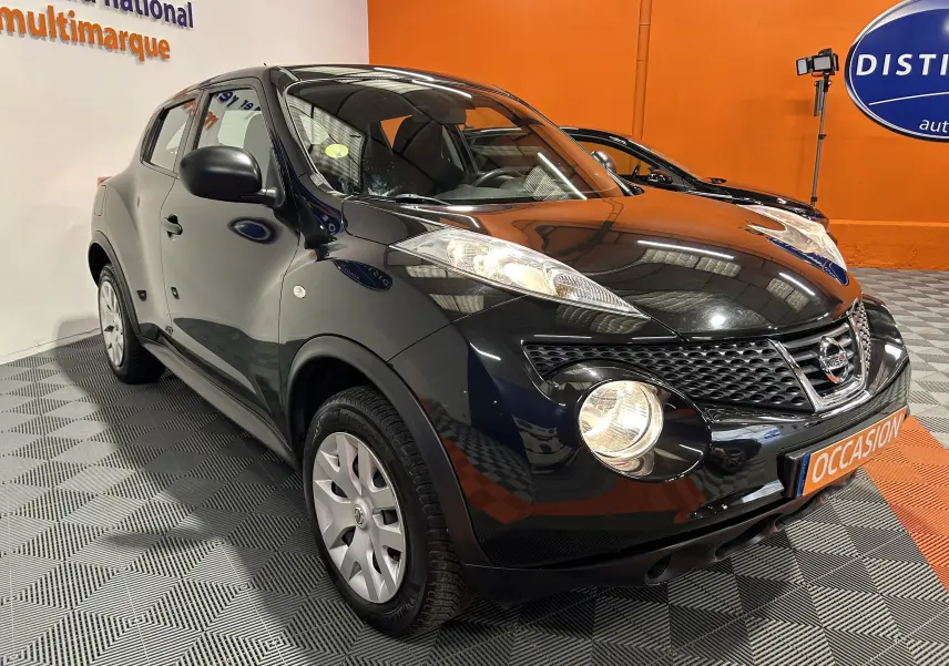 Vue 3/4 avant droite d'un Nissan Juke noir métal de 2012 avec attelage, en showroom sur sol damier.
