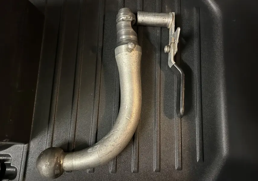 Gros plan sur l'attelage métallique détachable posé sur un fond noir, accessoire du Nissan Juke noir métal.