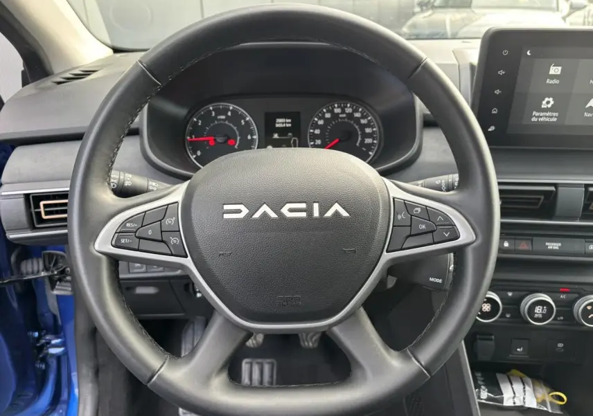 Vue intérieure centrée sur le volant noir Dacia avec tableau de bord et écran tactile du Sandero Stepway Bleu Iron 2025.