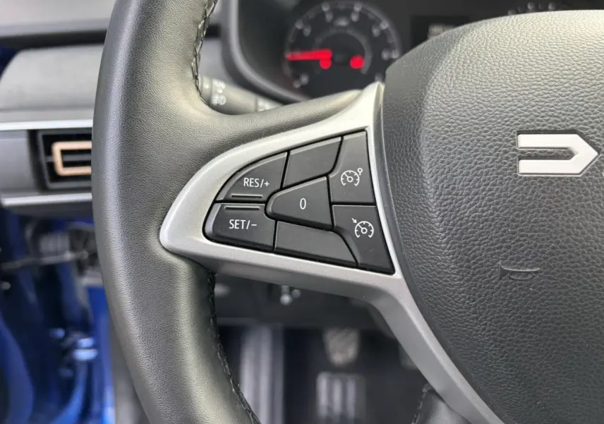 Gros plan sur le volant côté gauche du Dacia Sandero Stepway Bleu Iron, avec commandes de régulateur de vitesse visibles.
