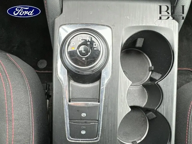 Vue plongeante sur la commande rotative de boîte automatique et porte-gobelets du Ford Kuga gris Solar Métallisée.