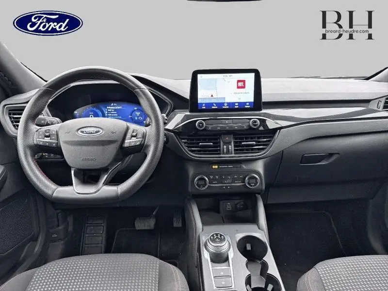 Vue intérieure avant du tableau de bord et volant cuir multifonction du Ford Kuga gris Solar, avec écran tactile central et console moderne.