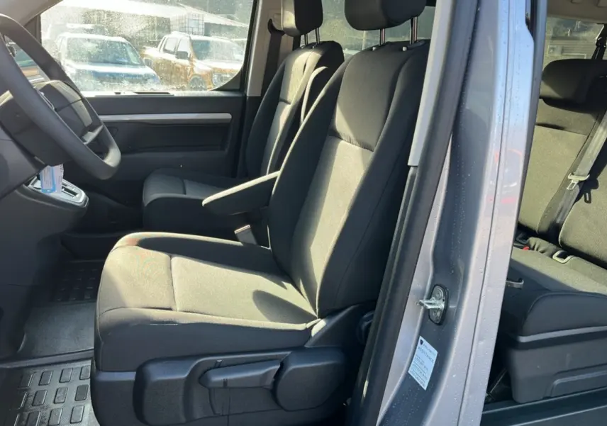 Intérieur du Peugeot Traveller gris acier vu côté gauche, montrant les sièges avant avec accoudoir central.
