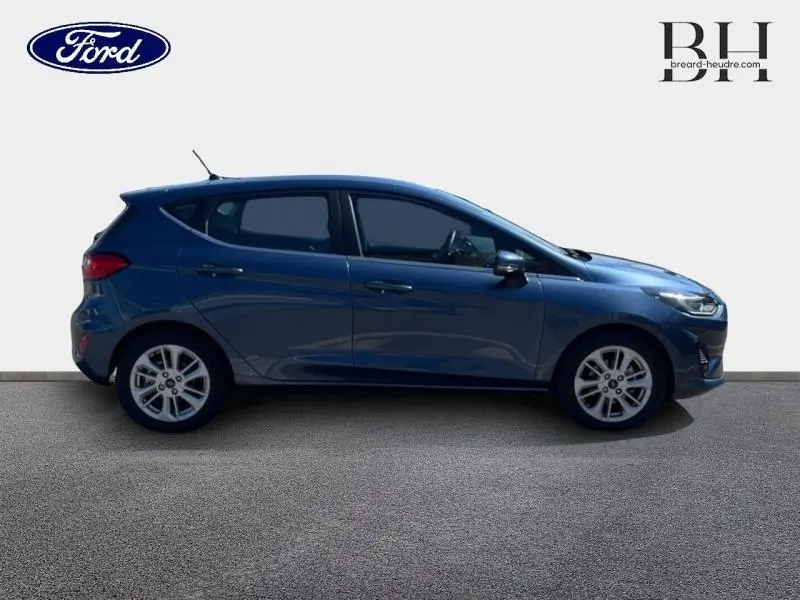 Vue de profil côté gauche d'une Ford Fiesta 2022 bleu azur métallisé avec jantes alliage et poignées ton carrosserie.