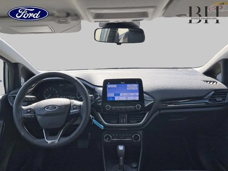 Vue intérieure frontale du tableau de bord noir de la Ford Fiesta 2022 avec écran tactile et volant cuir.