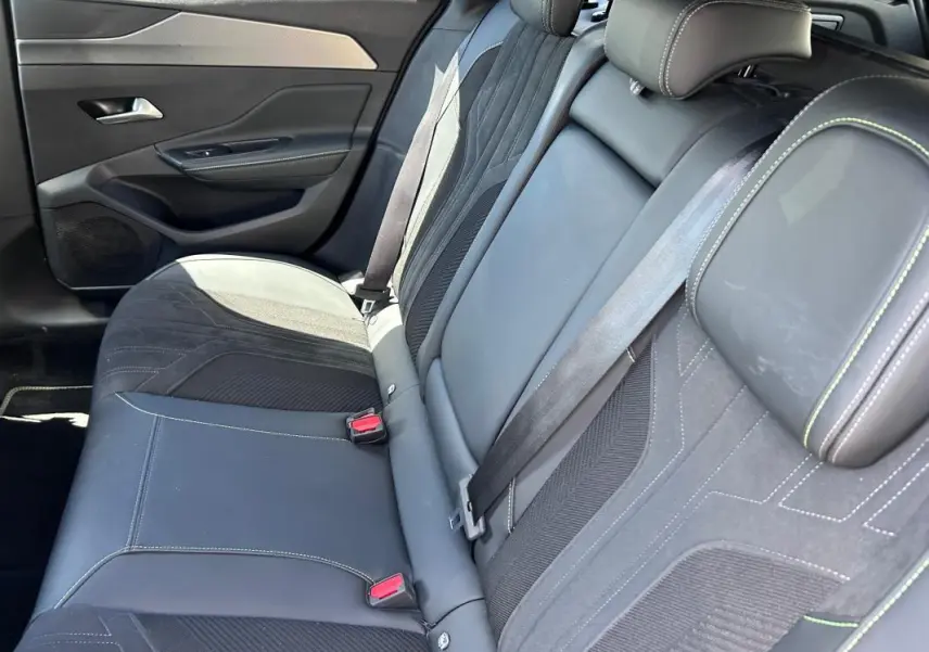 Vue intérieure des sièges arrière en cuir noir avec surpiqûres vertes d'une Peugeot 308 SW PHEV 225 GT 2023.