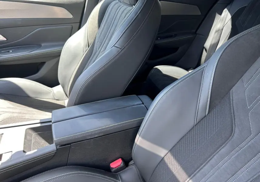 Vue intérieure rapprochée des sièges avant noirs et de l'accoudoir central du Peugeot 308 SW PHEV 225 GT 2023.