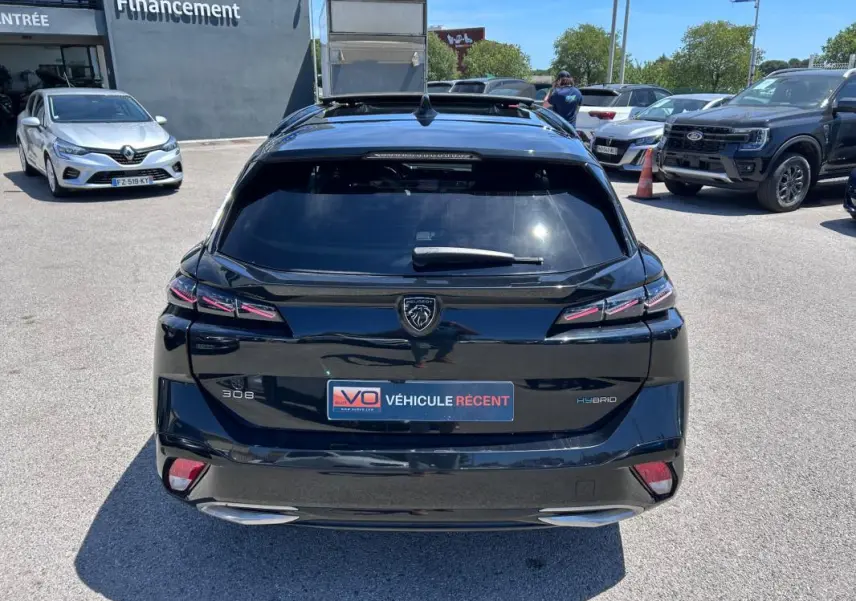 Vue arrière d'une Peugeot 308 SW PHEV 225 e-EAT8 GT noire avec feux LED et double sortie d'échappement visible.