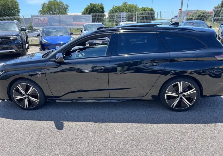 Vue latérale droite d'une Peugeot 308 SW PHEV noire 2023 avec jantes alliage 18 pouces et toit ouvrant électrique.