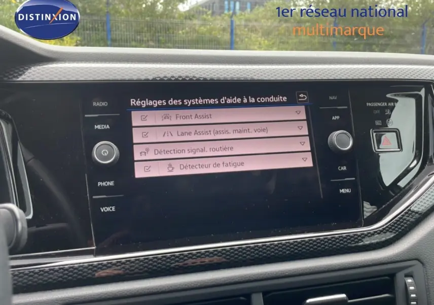 Vue rapprochée de l’écran tactile central du Volkswagen Polo blanc, affichant les réglages des aides à la conduite.