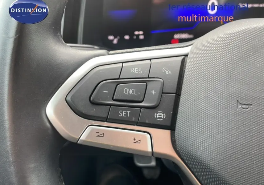 Gros plan sur les commandes au volant à gauche d'une Volkswagen Polo blanche, avec boutons de régulateur de vitesse.