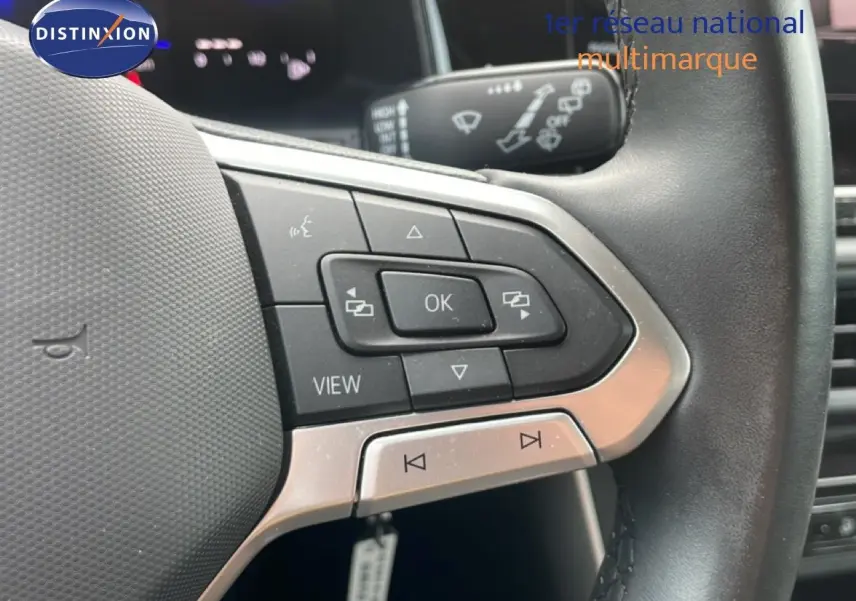 Gros plan sur les commandes au volant cuir noir d'une Volkswagen Polo blanche, mettant en valeur les boutons multifonctions.