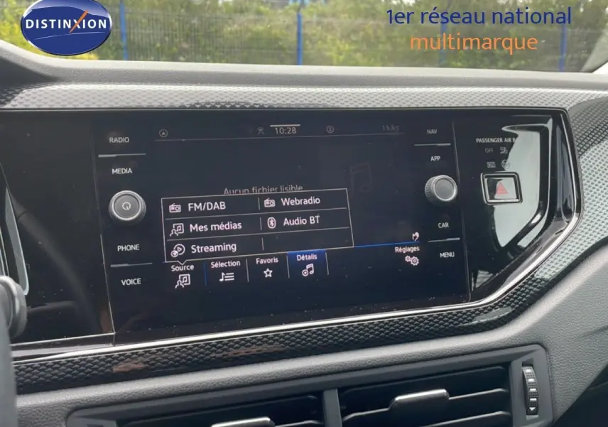Vue rapprochée de l'écran multimédia tactile du tableau de bord de la Volkswagen Polo blanche, affichant les options audio.