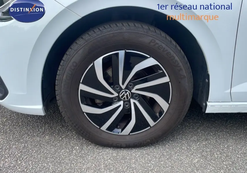 Gros plan sur la roue avant gauche d'une Volkswagen Polo blanc pur, avec jante alliage bicolore au design moderne.